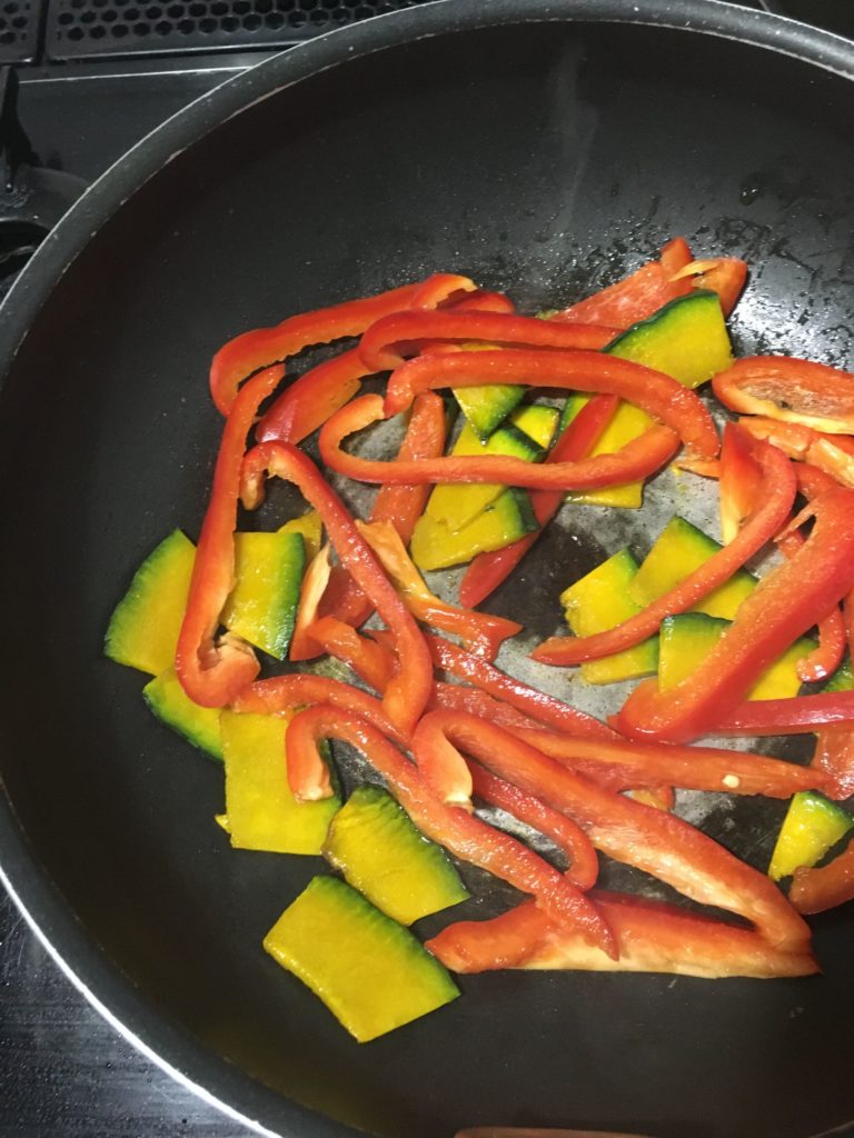 少量の油で炒めているパプリカとカボチャ