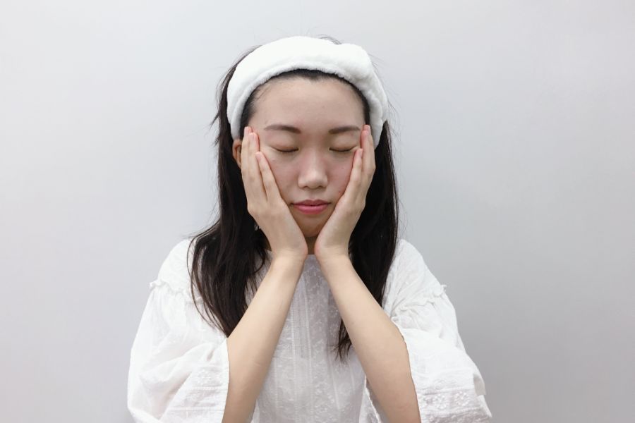 ほほを包み込むようにスキンケアをする女性