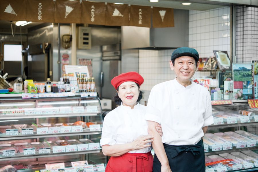 お店の前で腕を組む中野晴之さん 勝美さんご夫妻