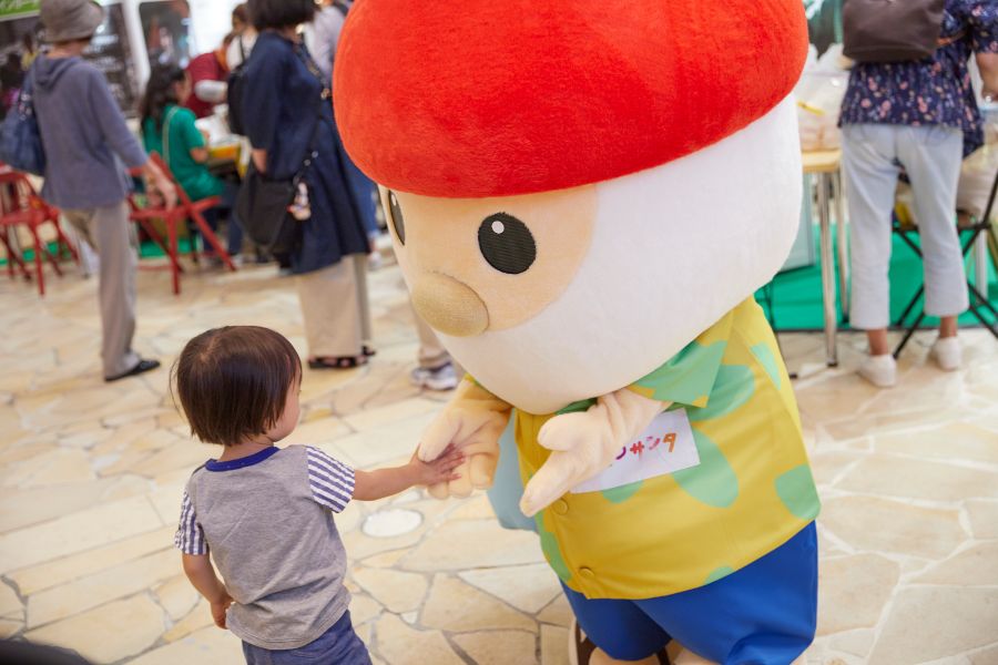 アロハシャツ姿のＨ2Ｏサンタと握手する子供