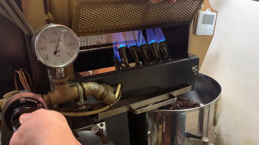 焙煎機の火加減を調整する店主