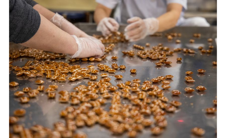 裁断機でカットされた飴を仕分けているところ