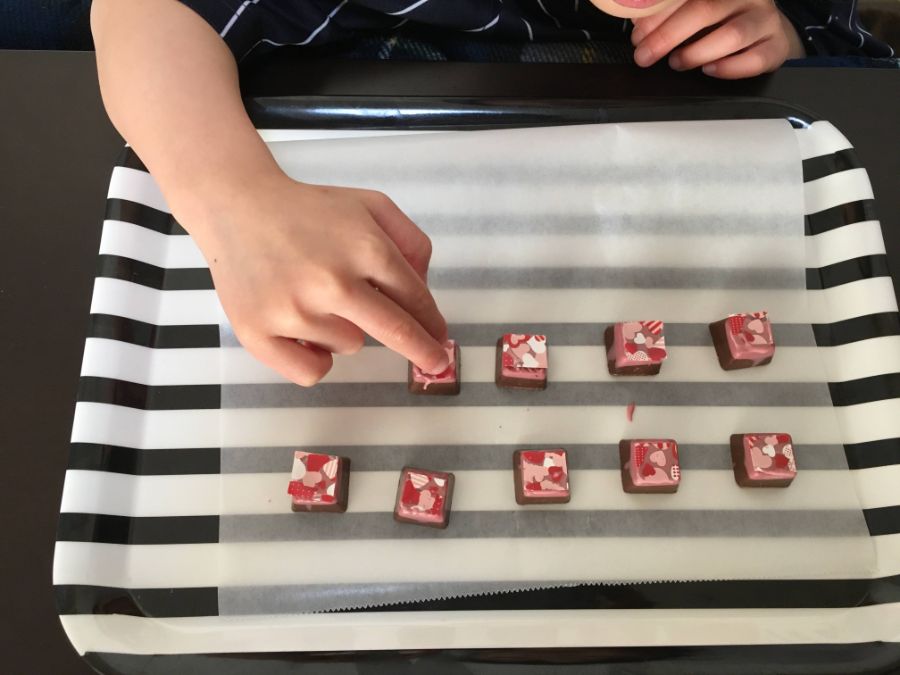 トレーの上でチョコに転写シートを貼り付ける作業