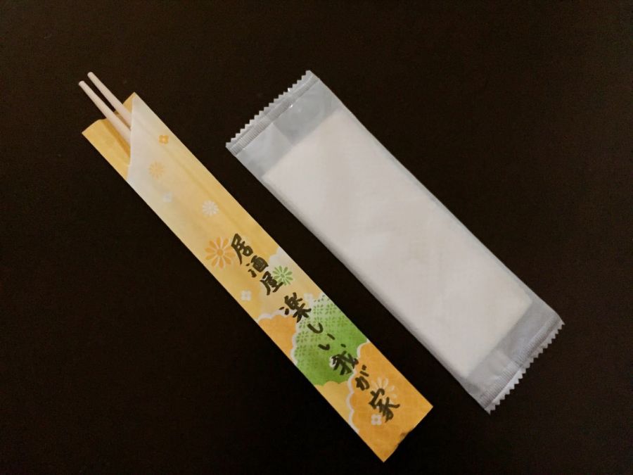 おしぼりと使い捨ての箸。箸袋には「居酒屋 楽しい我が家」の文字