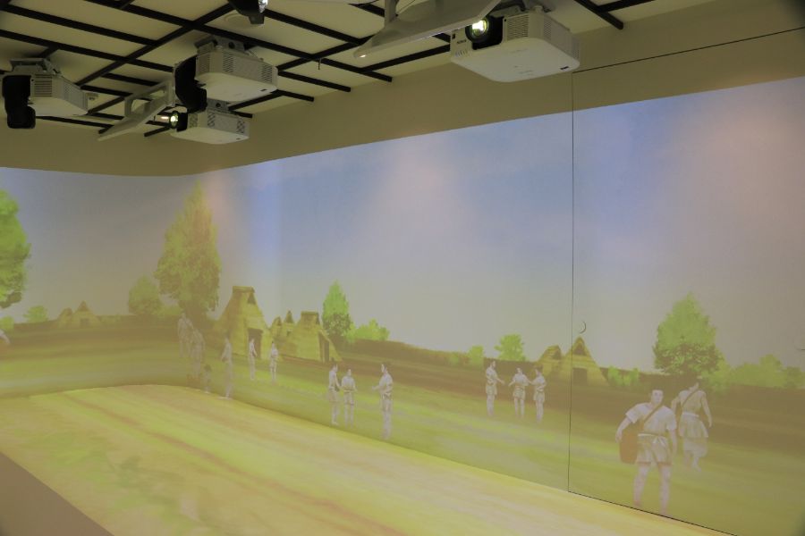 弥生時代の人々（イラスト）が映し出された映像