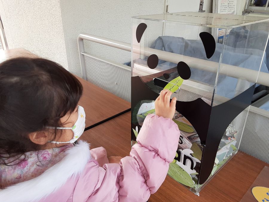 パンダのボックスにメッセージカードを入れる子ども