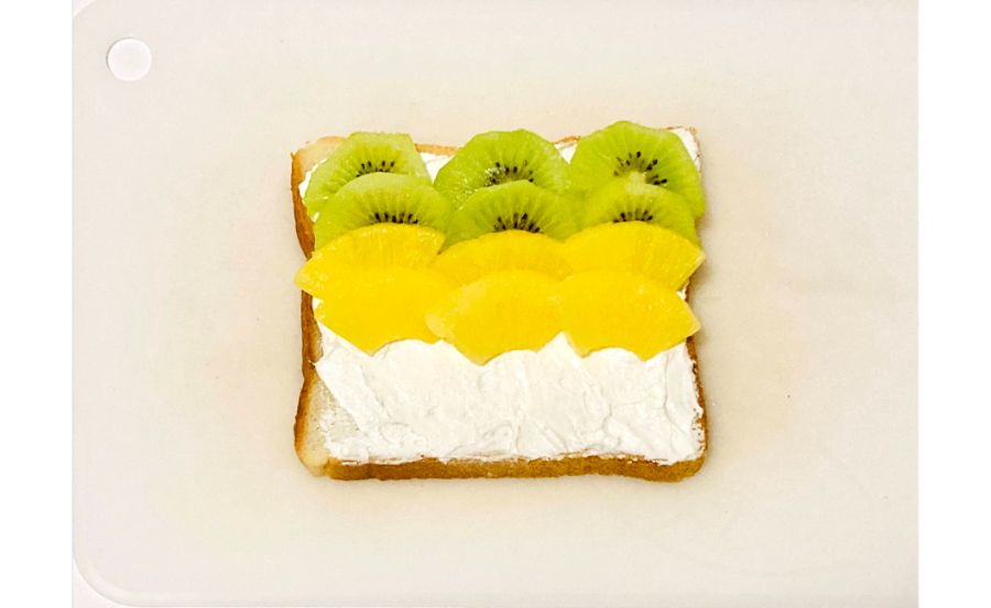 生クリームをぬった食パンにキウイとパインをのせている