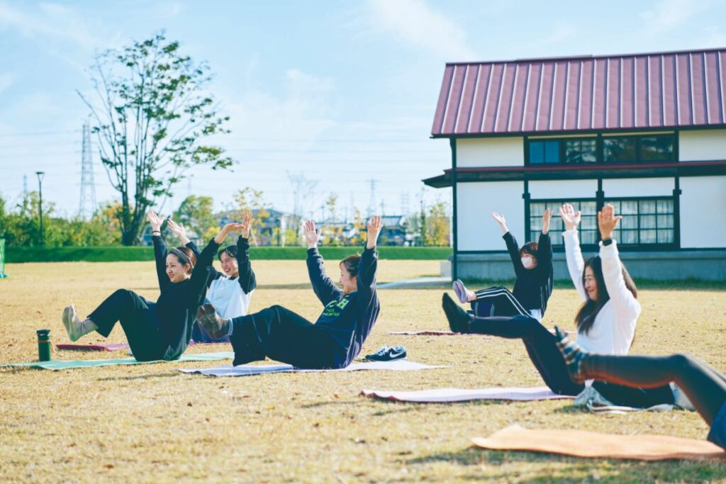 両手を上にあげてヨガをする女性たち