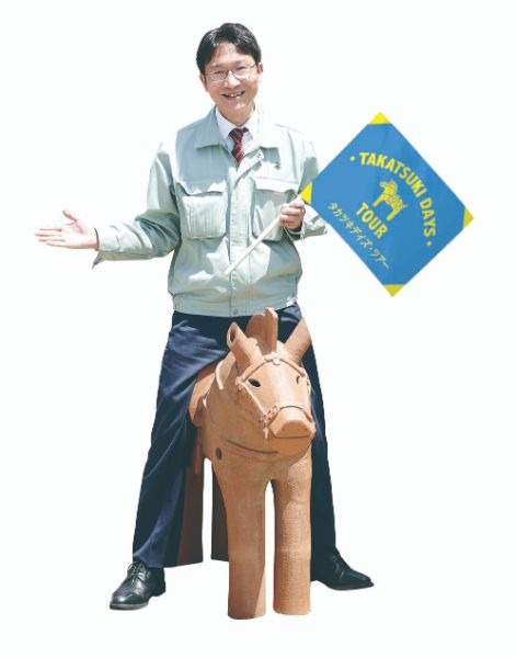 旗を持って埴輪にまたがるツアーガイドの男性