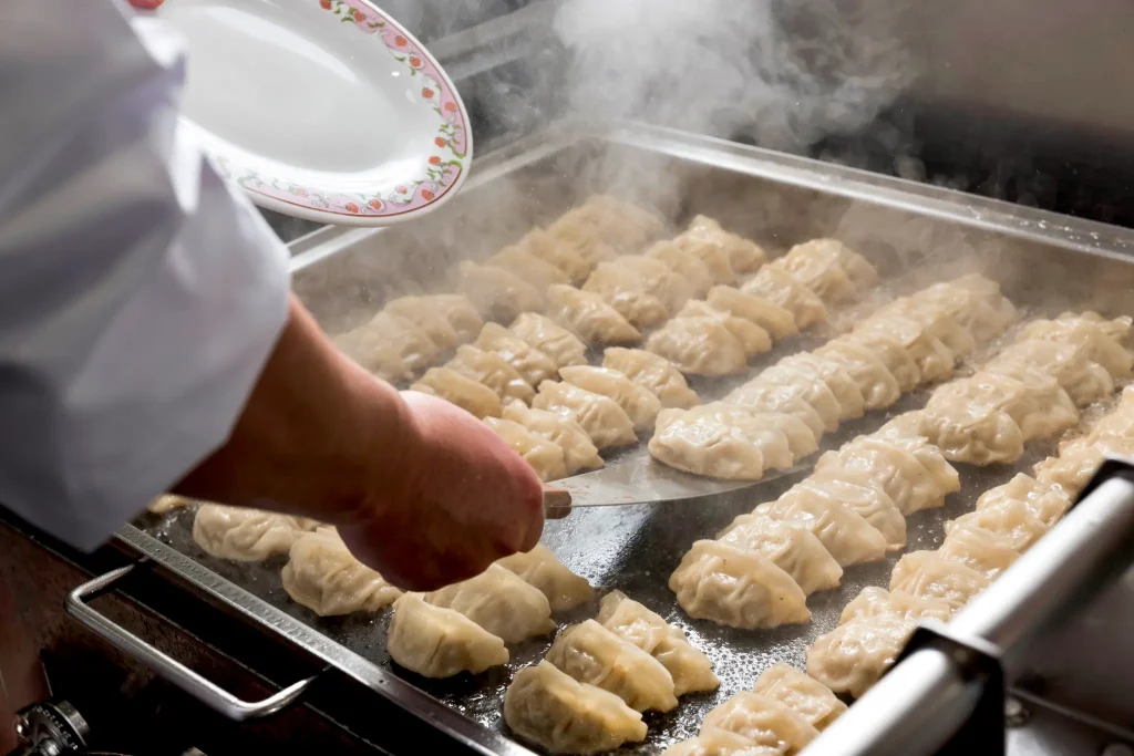 餃子の王将の鉄板で焼き上げられる餃子