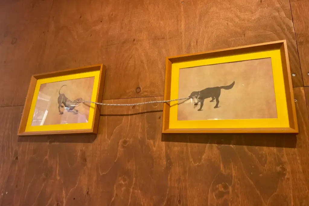 2匹の犬が紐を引っ張り合う額装された絵は、「CANOVA」のオーナー作