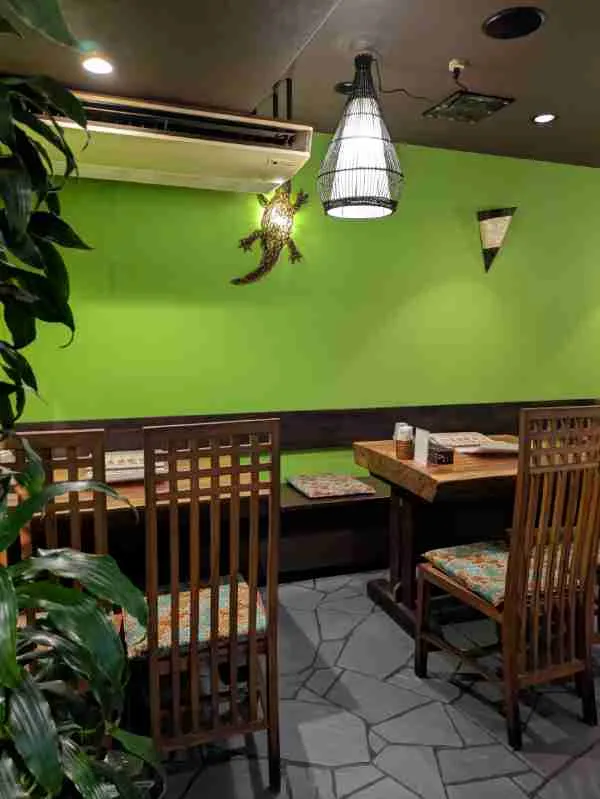 お店の中。緑色の壁に木調のテーブルといす。